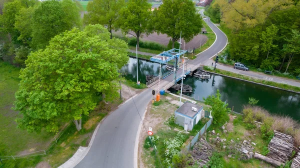 Flygfoto av en vindbro över en kanal eller flod i ett grönt landskap på landsbygden i Flandern, Belgien — Stockfoto