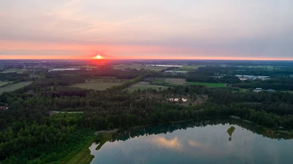 Vista aérea de una hermosa y dramática puesta de sol sobre un lago forestal reflejado en el agua, tiro de dron de paisaje — Foto de Stock