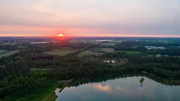 Pandangan udara tentang matahari terbenam yang indah dan dramatis di atas sebuah danau hutan yang tercermin dalam air, foto drone di permukaan laut — Stok Foto