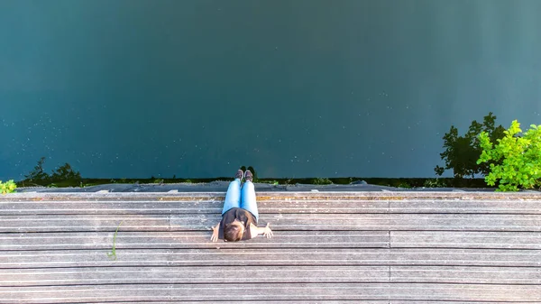 Concepto de vacaciones, disfrute y libertad. Vista aérea superior desde el retrato de estilo de vida de drones de una mujer joven a orillas de un río de madera junto al agua del río. — Foto de Stock