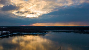 Bir orman gölü üzerinde güzel ve dramatik bir gün batımının havadan görüntüsü suya yansıyor, insansız hava aracı görüntüleri.