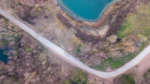 Widok z lotu ptaka malowniczego miejsca, gdzie na wiosnę przezroczysta turkusowa woda leśnego jeziora spotyka kamienny brzeg z drzewami. schwytany przez drona — Zdjęcie stockowe