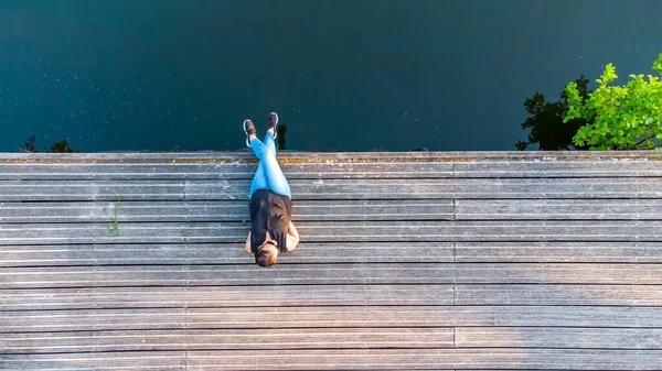 Concepto de vacaciones, disfrute y libertad. Vista aérea superior desde el retrato de estilo de vida de drones de una mujer joven a orillas de un río de madera junto al agua del río. — Foto de Stock