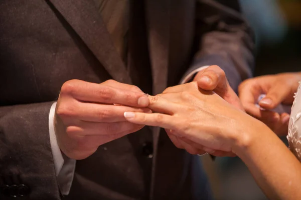 Closeup of bride putting a wedding ring onto the grooms finger. Couple exchanging wedding rings. — Stock Photo, Image