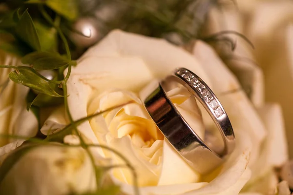 Fechar vista sobre flores brancas rosa com anéis de casamento em cores quentes e um cenário romântico — Fotografia de Stock