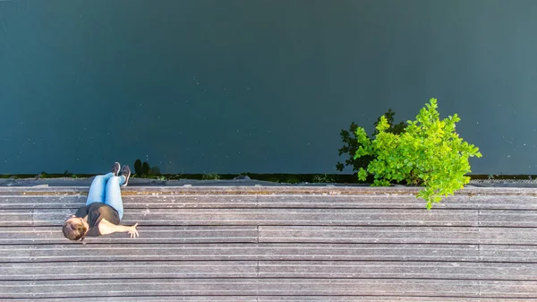 Concepto de vacaciones, disfrute y libertad. Vista aérea superior desde el retrato de estilo de vida de drones de una mujer joven a orillas de un río de madera junto al agua del río. — Foto de Stock