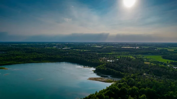 Vista aérea de una hermosa y dramática puesta de sol sobre un lago forestal reflejado en el agua, tiro de dron de paisaje — Foto de Stock