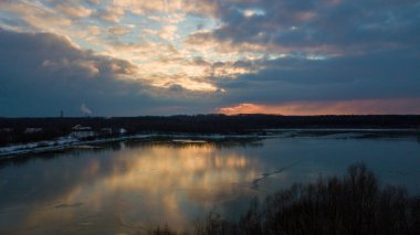 Bir orman gölü üzerinde güzel ve dramatik bir gün batımının havadan görüntüsü suya yansıyor, insansız hava aracı görüntüleri.