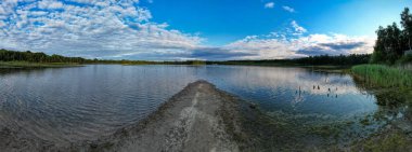 Suya yansıyan bir orman gölü üzerindeki güzel ve dramatik bir günbatımının hava manzarası.