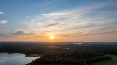 Göl kıyısında dramatik ve renkli bir gün batımının insansız hava aracı tarafından çekilen hava görüntüsü. Doğa manzarası. Avrupa 'da doğa. Yansıma, mavi gökyüzü ve sarı güneş ışığı. Gün doğumunda manzara veya
