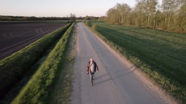 Spectaculaire luchtfoto van een man die tijdens zonsondergang wandelt in de velden van het Wilde platteland — Stockvideo