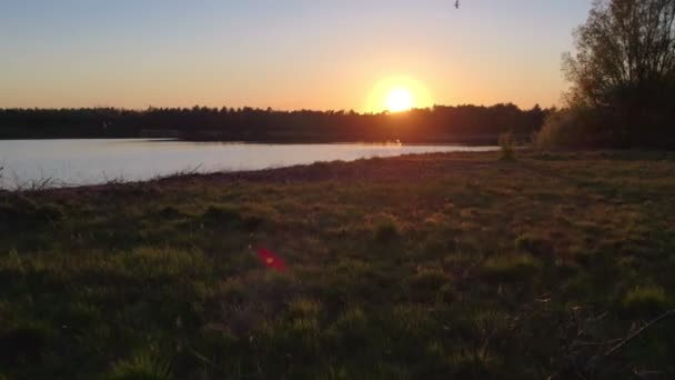 Flygfoto med en drönare av en sjö landskap vid solnedgången, sol och himmel återspeglas i vattnet — Stockvideo