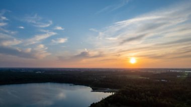 Göl kıyısında dramatik ve renkli bir gün batımının insansız hava aracı tarafından çekilen hava görüntüsü. Doğa manzarası. Avrupa 'da doğa. Yansıma, mavi gökyüzü ve sarı güneş ışığı. Gün doğumunda manzara veya