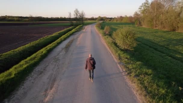 Spectaculaire luchtfoto van een man die tijdens zonsondergang wandelt in de velden van het Wilde platteland — Stockvideo