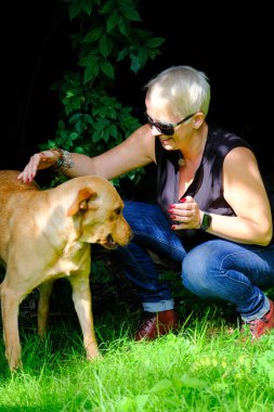Yakışıklı kadın arka bahçede Mutlu Altın Labrador Köpeği 'yle oynuyor. 