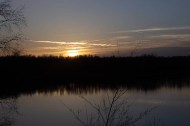 Orman gölünün üzerinde dramatik bir gün batımı