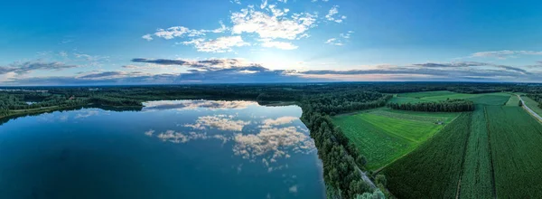 Aerial panorama view of a beautiful and dramatic sunset over a forest lake reflected in the water, landscape drone shot — Stock Photo, Image