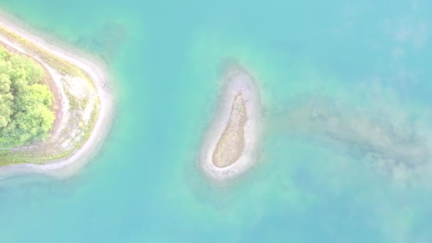 오염되지 않은 섬의 해변, 자연 경관 및 풍경 앞에서 연결되어 있는 작은 모래 띠로 이루어진 높은 각도의 드론 비행 — 비디오
