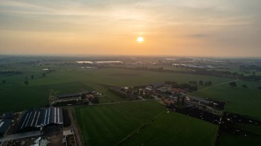 Mavi gökyüzünde tarlaları sürülen ve sürülmemiş tarlaları ve ağaçları olan dalgalı bir tarım arazisinin insansız hava aracı.