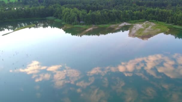 Golvend wateroppervlak met wazige reflectie van de lucht. Rippled water textuur met wazige reflectie in fel zonlicht. Rustig landschap met bosmeer — Stockvideo