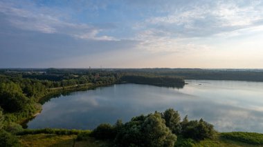 Göl kıyısında dramatik ve renkli bir gün batımının insansız hava aracı tarafından çekilen hava görüntüsü. Doğa manzarası. Avrupa 'da doğa. Yansıma, mavi gökyüzü ve sarı güneş ışığı. Gün doğumunda manzara veya