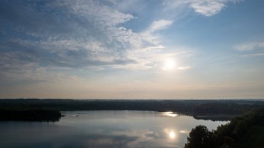 Göl kıyısında dramatik ve renkli bir gün batımının insansız hava aracı tarafından çekilen hava görüntüsü. Doğa manzarası. Avrupa 'da doğa. Yansıma, mavi gökyüzü ve sarı güneş ışığı. Gün doğumunda manzara veya