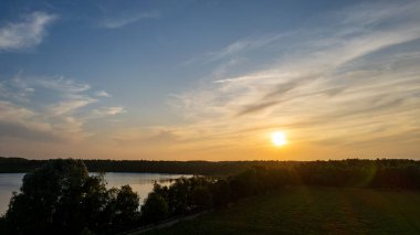 Göl kıyısında dramatik ve renkli bir gün batımının insansız hava aracı tarafından çekilen hava görüntüsü. Doğa manzarası. Avrupa 'da doğa. Yansıma, mavi gökyüzü ve sarı güneş ışığı. Gün doğumunda manzara veya