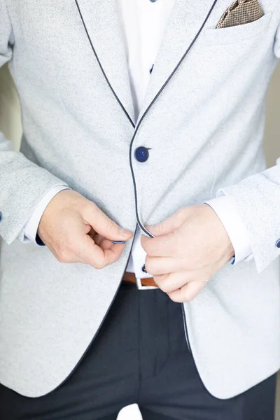 Groom wears a vest and closes with two hands button links in morning wedding preparation — Stock Photo, Image