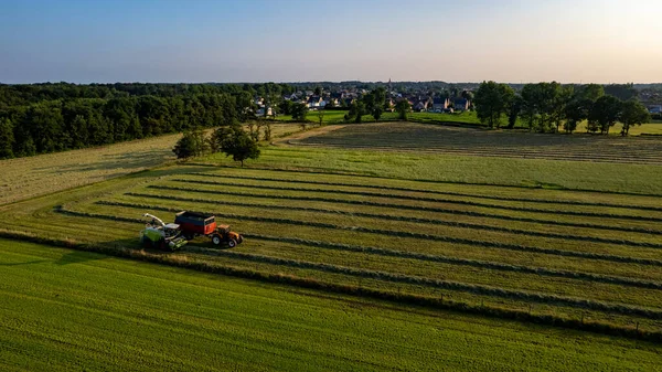 Aerial of tractor baler making straw bales in field after wheat harvest in summer on farm — Stock Photo, Image
