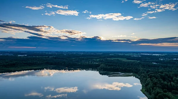 Vista aérea de una hermosa y dramática puesta de sol sobre un lago forestal reflejado en el agua, tiro de dron de paisaje — Foto de Stock