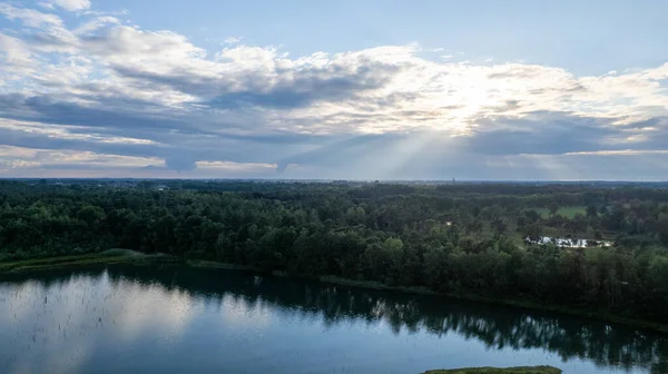 Luchtfoto van een prachtige en dramatische zonsondergang boven een bos meer weerspiegeld in het water, landschap drone shot — Stockfoto