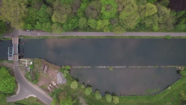 Aerial view of the canal, showing a draw bridge from above. Spring meadows and trees on the river bank in Rijkevorsel, Flanders, Belgium — Stock Video