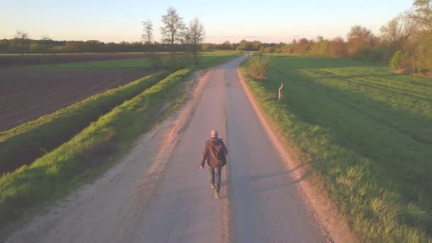 Видовищний повітряний вид людини, що ходить по полях дикої сільської місцевості під час заходу сонця — стокове відео