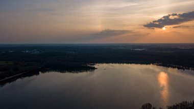 Göl kıyısında dramatik ve renkli bir gün batımının insansız hava aracı tarafından çekilen hava görüntüsü. Doğa manzarası. Avrupa 'da doğa. Yansıma, mavi gökyüzü ve sarı güneş ışığı. Gün doğumunda manzara veya