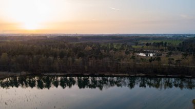 Göl kıyısında dramatik ve renkli bir gün batımının insansız hava aracı tarafından çekilen hava görüntüsü. Doğa manzarası. Avrupa 'da doğa. Yansıma, mavi gökyüzü ve sarı güneş ışığı. Gün doğumunda manzara veya