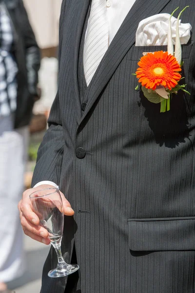 Жених держит бокал или флейту шампанского на фоне друзей на природе на свадебной церемонии. Закрывай. Тост. — стоковое фото