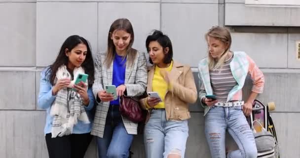 Kelompok multietnis teman-teman wanita muda yang cantik berdiri menghadap dinding menggunakan ponsel pintar — Stok Video