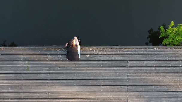 Mooi vrouwtje op de pier bij de zee. Zomervakantie concept. Luchtbeelden genomen met een drone. — Stockvideo