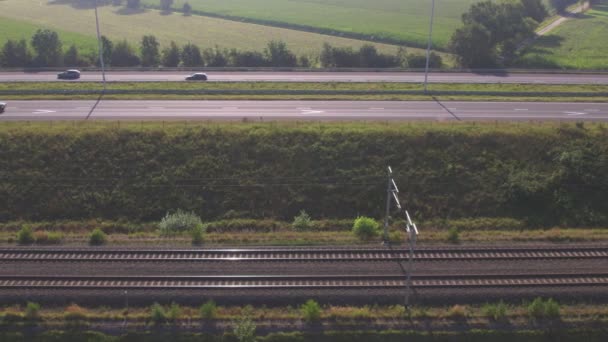 Bovenaanzicht van auto 's die tijdens de zomer in België, Europa, op een snelweg naast een spoorweg rijden. Luchtfoto met drone. — Stockvideo