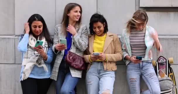 Grupo multiétnico de hermosas amigas jóvenes de pie contra una pared usando teléfonos inteligentes móviles — Vídeos de Stock