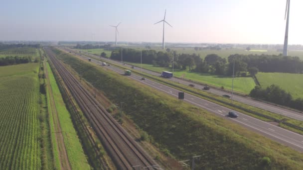 Вид сверху на автомобили, едущие по шоссе рядом с железной дорогой летом в Бельгии, Европа. Аэросъемка с беспилотником. — стоковое видео