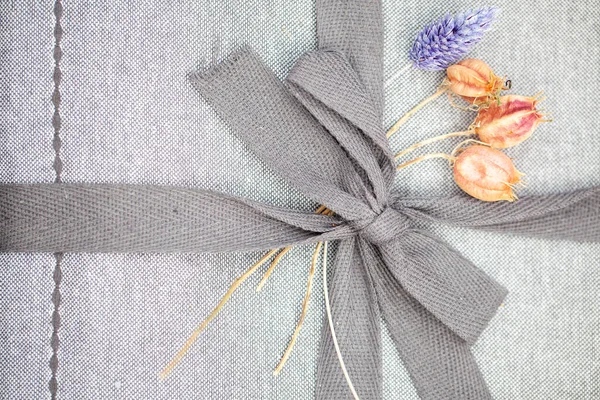 Stäng upp söt grå rosett på en grå linnen förpackning — Stockfoto