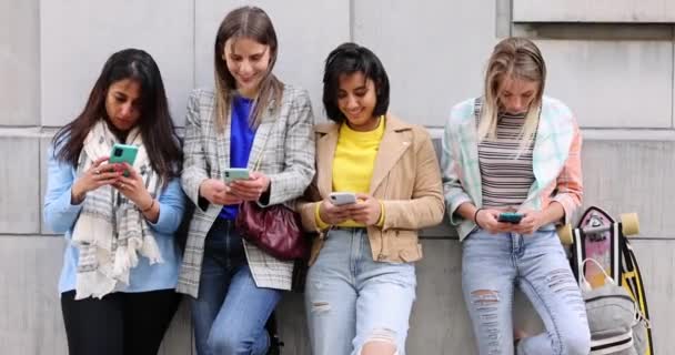 Grupo multiétnico de hermosas amigas jóvenes de pie contra una pared usando teléfonos inteligentes móviles — Vídeos de Stock