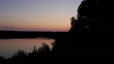 Kırsal kesim dramatik ve renkli bir günbatımı uçuşu bir orman gölü üzerinde, bir insansız hava aracı üzerinde.