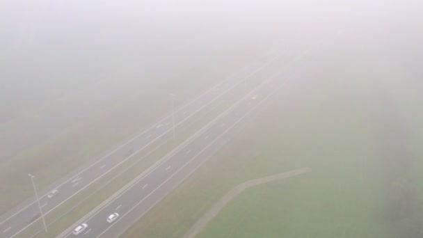 Blick aus der Vogelperspektive auf Autos, die an einem nebligen Sommertag in Belgien, Europa, auf einer Autobahn neben einer Eisenbahn fahren. Luftaufnahme mit Drohne. — Stockvideo