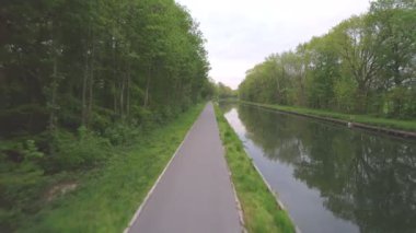 Ağaçlarla çevrili bir kanal boyunca seyahat eden hava görüntüleri.