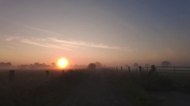 Huzurlu ve güzel bir gün doğumu sislerle kaplı bir alanı aydınlatarak harika bir kırsal ortam yaratıyor.