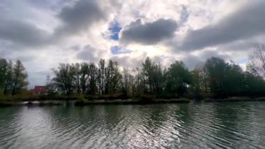 Dalgalanan yansıtıcı nehrin üzerindeki kaotik gökyüzü, dalgalanan nehir yansımaları üzerinde güçlü bulut oluşumları gerilim yaratır.