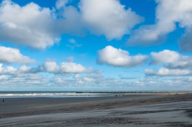 Uzaktaki iskelede sakin bir sahil manzarası ve rahatlatıcı bulutlar promosyon görüntüleri için ideal.