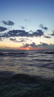 Yuvarlanan dalgalar üzerinde altın güneş ışığı, engin mavi gökyüzü ile sakin deniz, yumuşak okyanus ve huzurlu ruh hali ile dramatik gökyüzü.